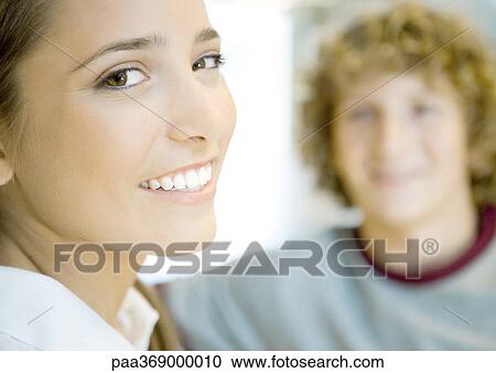 Teenage girl smiling at camera, teenage boy in background View Large Photo Image Stock Image - Teenage girl smiling at camera, teenage boy in background. Fotosearch
