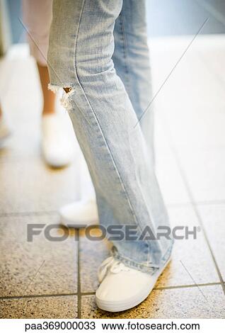 Teenage girl wearing jeans with hole at the knee, close-up of knee down View Large Photo Image Stock Image - Teenage girl wearing jeans with hole at the knee, close-up of knee down. Fotosearch