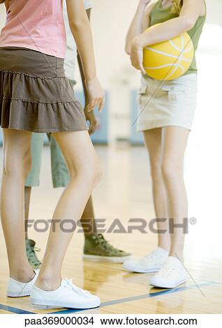 Teenage girls standing in circle, one holding ball, in school gym, chest down View Large Photo Image Picture - Teenage girls standing in circle, one holding ball, in school gym, chest down. Fotosearch