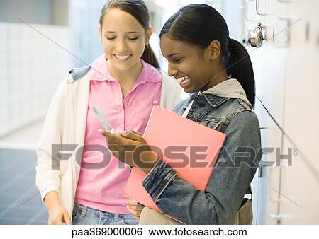 Two teenage girls looking at cell phone, next to lockers View Large Photo Image Stock Photograph - Two teenage girls looking at cell phone, next to lockers. Fotosearch