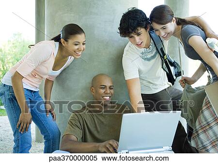 Stock Photography - Group of college students gathered around young man with laptop. Fotosearch