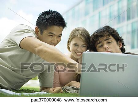 Stock Photo - Three college students using laptop outdoors. Fotosearch