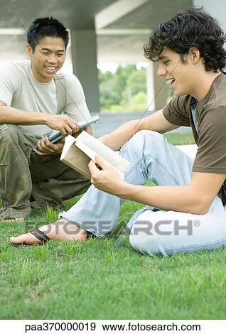 Stock Photo - Two college students sitting in grass, studying. Fotosearch