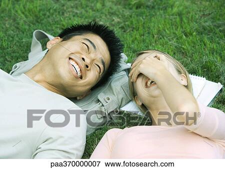 Young couple lying on grass, laughing View Large Photo Image Stock Photo - Young couple lying on grass, laughing. Fotosearch