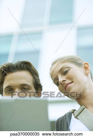 Stock Photography - Young couple using laptop together, low angle view. Fotosearch