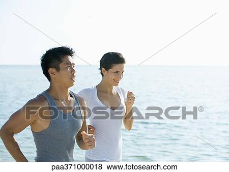 Couple running next to sea View Large Photo Image Stock Photo - Couple running next to sea. Fotosearch