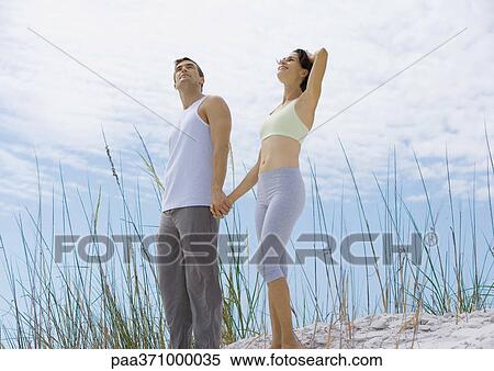 Couple standing holding hands in dunes View Large Photo Image Stock Photography - Couple standing holding hands in dunes. Fotosearch