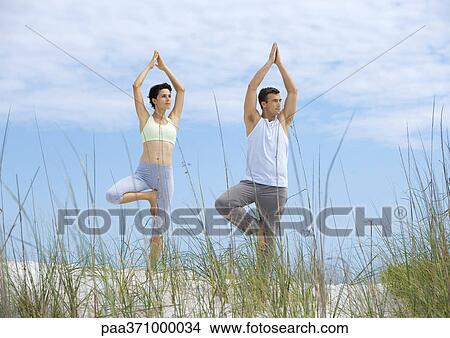 Couple standing in yoga tree pose on beach View Large Photo Image Picture - Couple standing in yoga tree pose on beach. Fotosearch