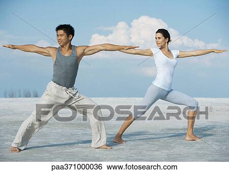 Man and woman doing yoga on beach View Large Photo Image Stock Photograph - Man and woman doing yoga on beach. Fotosearch