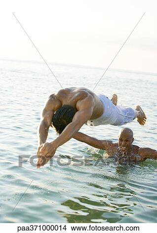Man diving into water from second man's shoulders View Large Photo Image Picture - Man diving into water from second man's shoulders. Fotosearch