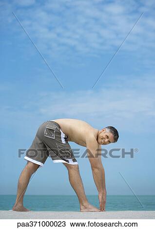 Man doing stretches on beach View Large Photo Image Stock Image - Man doing stretches on beach. Fotosearch