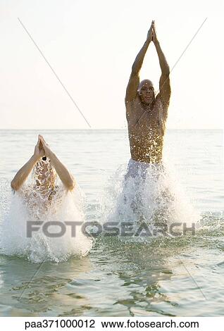Two men emerging from water with hands over heads View Large Photo Image Stock Image - Two men emerging from water with hands over heads. Fotosearch