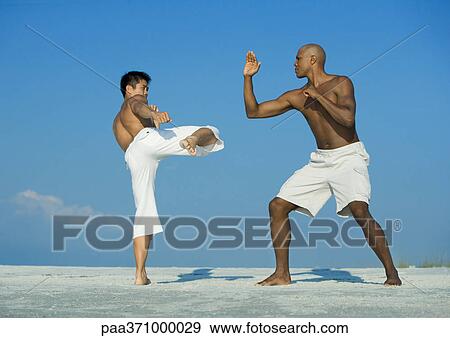 Two men practicing martial arts on beach View Large Photo Image Stock Photo - Two men practicing martial arts on beach. Fotosearch