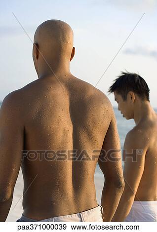 Two men standing on beach View Large Photo Image Stock Photo - Two men standing on beach. Fotosearch