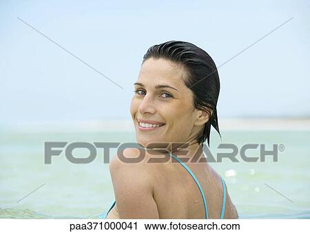 Woman in sea, smiling over shoulder at camera View Large Photo Image Stock Image - Woman in sea, smiling over shoulder at camera. Fotosearch
