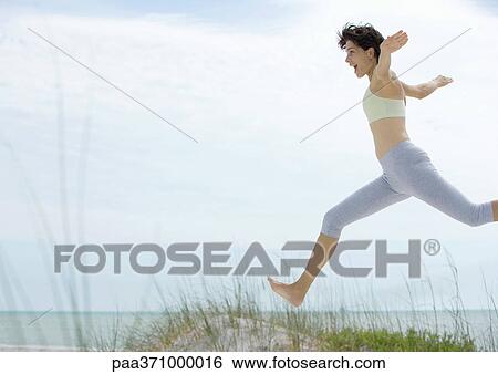 Stock Photograph - Woman jumping in dunes. Fotosearch