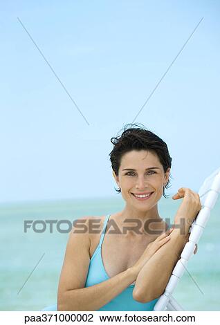 Woman sitting on lounge chair on beach View Large Photo Image Stock Image - Woman sitting on lounge chair on beach. Fotosearch