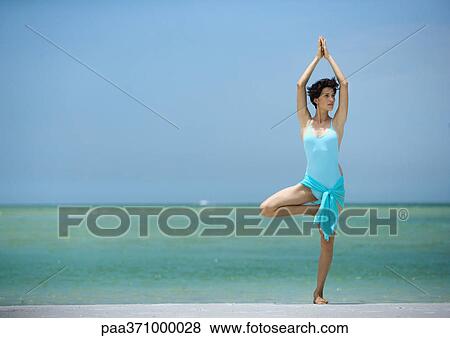 Woman standing in tree pose on beach View Large Photo Image Stock Photo - Woman standing in tree pose on beach. Fotosearch