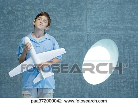 Stock Image - Boy holding toy airplane, closing eyes. Fotosearch