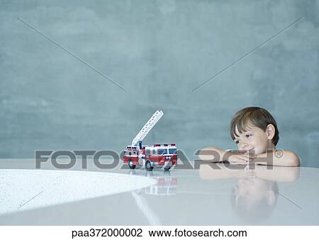 Boy looking longingly at toy firetruck View Large Photo Image Stock Image - Boy looking longingly at toy firetruck. Fotosearch