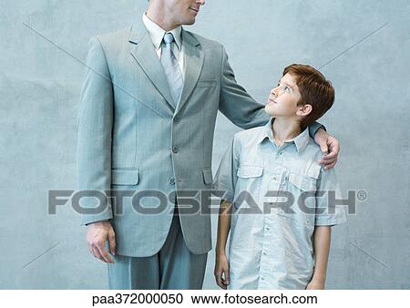 Boy looking up admiringly at businessman View Large Photo Image Stock Image - Boy looking up admiringly at businessman. Fotosearch
