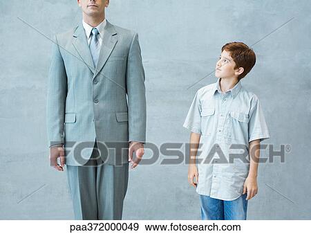Boy looking up admiringly at businessman View Large Photo Image Stock Photo - Boy looking up admiringly at businessman. Fotosearch