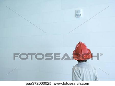 Stock Photography - Boy wearing fireman's hat, rear view. Fotosearch