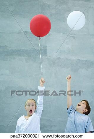 Stock Image - Two children holding balloons, shouting. Fotosearch
