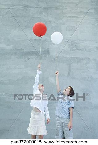 Two children holding helium balloons View Large Photo Image Stock Photography - Two children holding helium balloons. Fotosearch