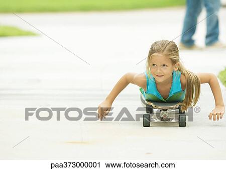 Stock Image - Girl lying on skateboard. Fotosearch
