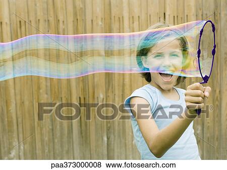 Girl making bubble with wand View Large Photo Image Stock Photo - Girl making bubble with wand. Fotosearch