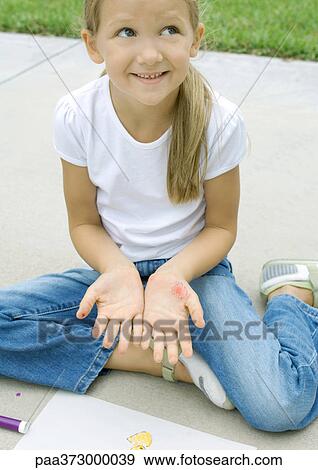 Girl sitting with drawing materials, showing marks on palms View Large Photo Image Stock Photo - Girl sitting with drawing materials, showing marks on palms. Fotosearch