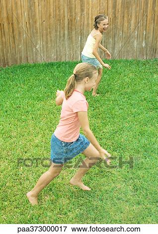 Stock Photo - Girls running in yard. Fotosearch