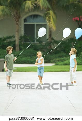 Suburban children holding balloons View Large Photo Image Stock Image - Suburban children holding balloons. Fotosearch