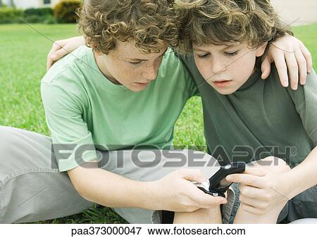 Stock Photo - Two boys looking at cell phone. Fotosearch