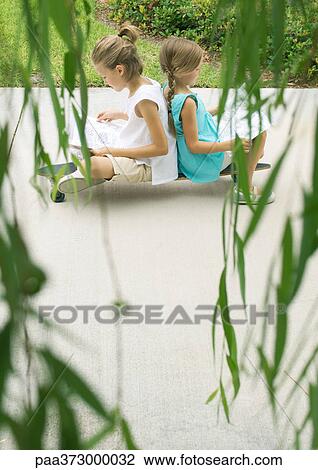Two girls reading back to back on skateboard View Large Photo Image Stock Image - Two girls reading back to back on skateboard. Fotosearch