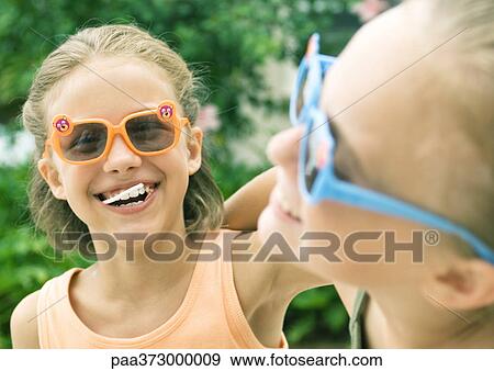 Two girls wearing sunglasses and laughing View Large Photo Image Stock Photo - Two girls wearing sunglasses and laughing. Fotosearch