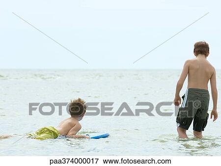 Boy floating on body board next to second boy, rear view View Large Photo Image Stock Photo - Boy floating on body board next to second boy, rear view. Fotosearch