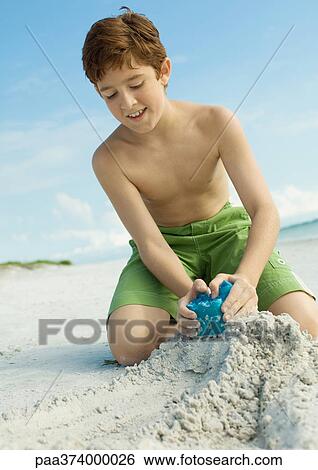 Boy making sand castle on beach View Large Photo Image Stock Photograph - Boy making sand castle on beach. Fotosearch