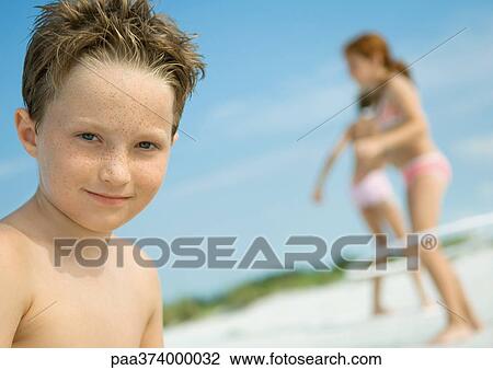 Boy smiling, children playing in background, on beach View Large Photo Image Stock Image - Boy smiling, children playing in background, on beach. Fotosearch