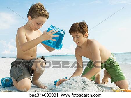 Boys building sand castle on the beach View Large Photo Image Stock Image - Boys building sand castle on the beach. Fotosearch