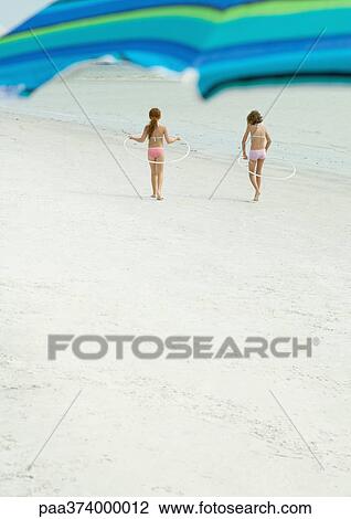 Stock Image - Children playing with hoops on the beach. Fotosearch