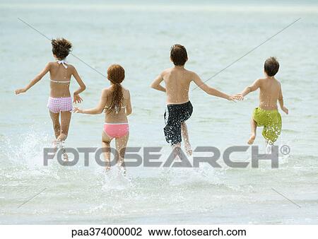 Stock Image - Children running in surf at beach. Fotosearch
