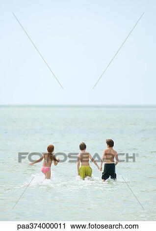 Stock Image - Children running in surf at beach. Fotosearch