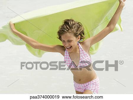Girl holding up towel in wind, on beach View Large Photo Image Stock Photo - Girl holding up towel in wind, on beach. Fotosearch