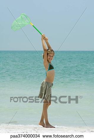 Girl on beach, holding up fishing net overhead View Large Photo Image Picture - Girl on beach, holding up fishing net overhead. Fotosearch