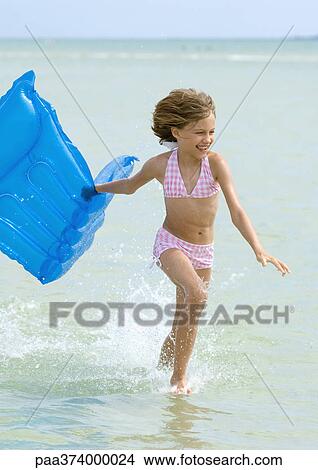 Girl running in surf at beach, carrying raft View Large Photo Image Picture - Girl running in surf at beach, carrying raft. Fotosearch