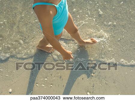 Stock Image - Girl walking in surf. Fotosearch