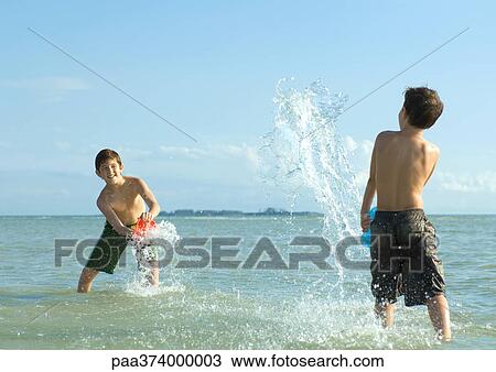 Two boys splashing in water at beach View Large Photo Image Stock Image - Two boys splashing in water at beach. Fotosearch