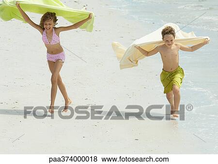 Two children running on beach, holding up towels in wind View Large Photo Image Stock Photo - Two children running on beach, holding up towels in wind. Fotosearch